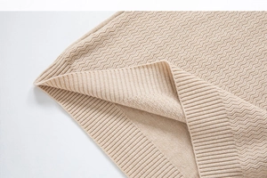 Close-up of beige knit sweater showing wave patterns and ribbed cuff textures
