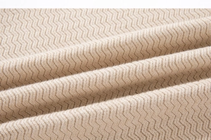 Macro detail of beige zigzag knit fabric showing texture and soft material on men's sweater