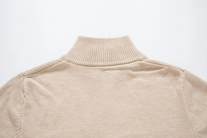 Detailed view of the ribbed knit collar and shoulder stitching on a beige sweater