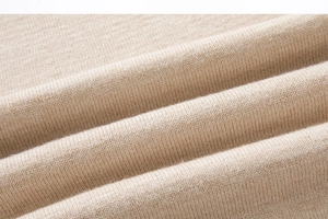 Macro shot of light beige knitted fabric texture showing premium soft stitching details