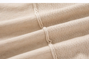 Close-up of beige knit sweater showing fine texture and professional stitching details