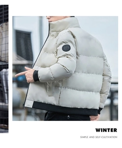 Detail van de lichtbeige winterjas met zwarte ribboorden en een ronde mouwbadge