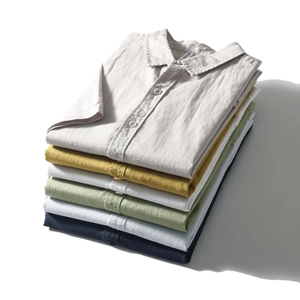 Close-up of stacked colorful cotton linen shirts showing rich fabric texture and lapel detail