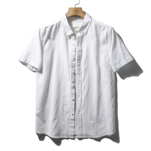 Detailed view of the white cotton short sleeve shirt showing fabric texture on a hanger