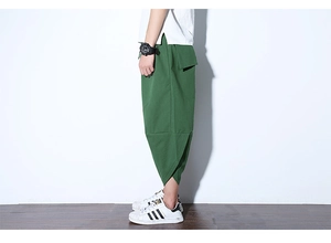 Dettaglio laterale dei pantaloni larghi in misto lino verde scuro con orli asimmetrici unici