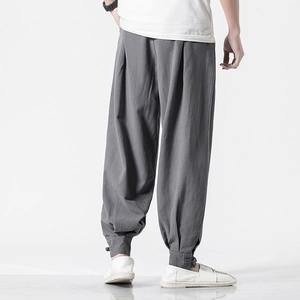 Back view of men's loose linen harem pants in grey with tapered buttoned cuffs