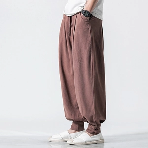 Men's loose linen harem pants in terracotta with drawstring waist and tapered cuffs
