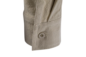Close-up of linen shirt cuff with resin button and detailed stitching in beige