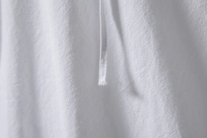 Macro-opname van de witte katoen-linnen textuur en hangende koordjes op het herenshirt
