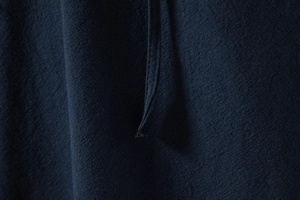 Detailopname van de nette stiksels en de donkerblauwe linnen textuur van de heren overhemd