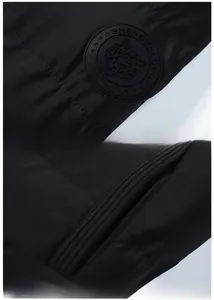 Detail of black winter jacket sleeve featuring a tiger badge and matte fabric stitching