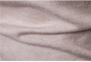 Vista ravvicinata della trama in maglia beige morbida e dettagli del tessuto maglione