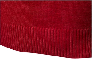 Dettaglio del maglione rosso a dolcevita con polsini a coste e trama a maglia fitta di qualità