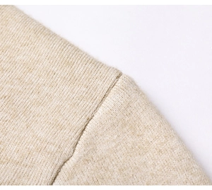 Dettaglio della spalla di un maglione in maglia beige con cuciture sottili e consistenza morbida