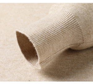 Dettaglio dei polsini a coste sul maglione lavorato a maglia color avena e trama fine