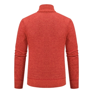 Macro detail of the orange knitted cardigan sweater showing textured fabric and ribbed hem
