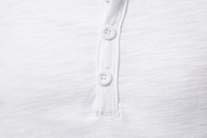 Detail view of white slub cotton fabric texture and button placket on a men's polo shirt