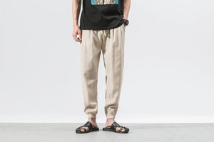 Detail of men's linen jogger pants featuring beige fabric texture and elastic drawstring waist