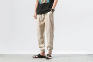 Detailed texture of beige linen fabric on men's drawstring harem pants with elastic cuffs