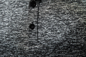 Vista macro del tessuto grigio catione con due bottoni neri su una classica scollatura Henley