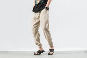 Detailed close-up of beige linen trousers featuring elastic waistband and drawstring cords
