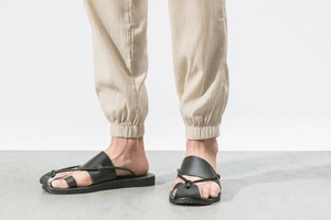 Detail of minimalist black leather sandals with cross straps and textured anti-slip soles