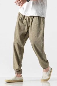 Detail of men's linen jogger pants featuring drawstring waist and olive green fabric texture
