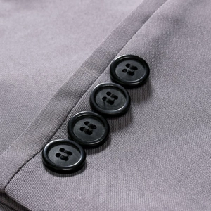 Close-up of four black buttons on a grey slim fit suit jacket sleeve with fine twill texture