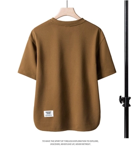 Detail of a brown short sleeve t-shirt with a brand label and unique curved hem design
