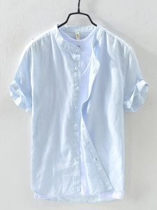 Detailed texture of light blue linen shirt featuring stand collar and button-down front