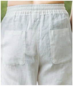 Close-up of white cotton linen pants featuring elastic high waist and large back pockets