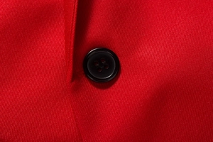 Macro shot of single-breasted black button on red twill fabric of men's slim suit jacket