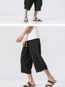 Detail of loose black linen pants showing breathable texture and woven drawstring waist
