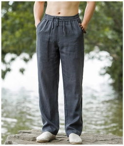 Detailed texture of dark grey linen trousers with drawstring waist and loose fit design