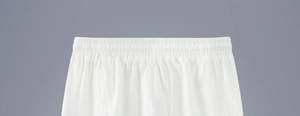 Detail of the elastic waistband on white cotton linen shorts with fine stitching