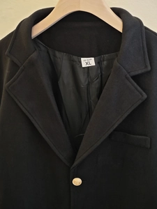 Détail d'un manteau en laine pour hommes avec bouton doré embossé et étiquette de taille XL