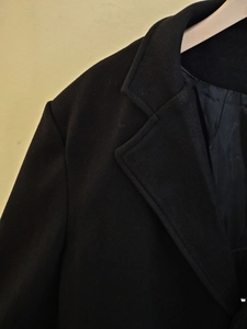 Vue détaillée d'un manteau en laine noir avec col à revers et doublure velours