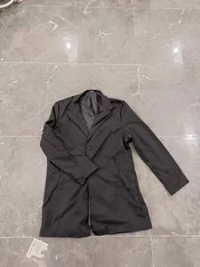 Detailed close-up of a men's classic black single-breasted trench coat with notch lapels