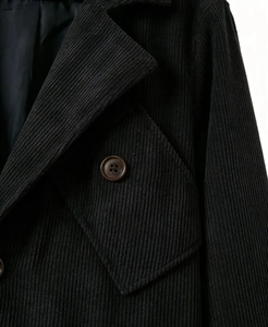 Detail of black corduroy blazer featuring notched lapels and textured vertical ribbing