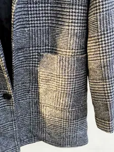 Detailed macro view of black and white houndstooth wool fabric with single button closure