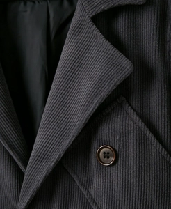 Detail of dark grey corduroy fabric texture and classic buttoned pocket on a blazer