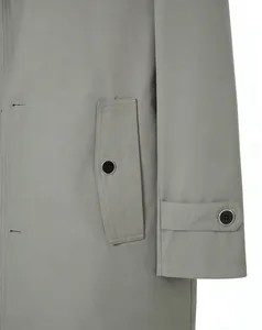 Close-up detail of grey trench coat showing premium fabric and pocket with black button