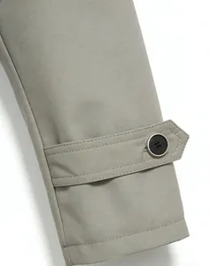 Close-up of adjustable cuff strap and black button on a classic light khaki trench coat