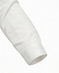 Detail of the white long-sleeve shirt cuff showing textured cotton linen fabric and stitching
