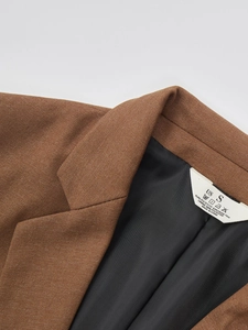 Close-up of brown blazer collar with clear twill texture and white fabric care label