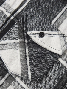 Close-up of herringbone fabric texture and chest pocket on a casual plaid shirt