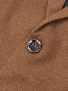 Detail of classic resin button and textured brown twill fabric on men's blazer jacket