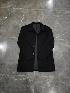 Detail view of black wool coat featuring a notch lapel, buttons, and grey inner lining