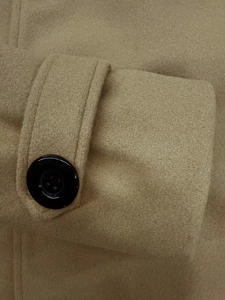Dettaglio della manica del cappotto color cammello con cinturino e bottone nero