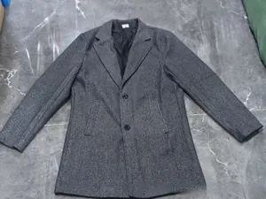 Λεπτομέρεια από σκούρο γκρι μάλλινο παλτό με κλασικό πέτο και κλείσιμο με κουμπιά